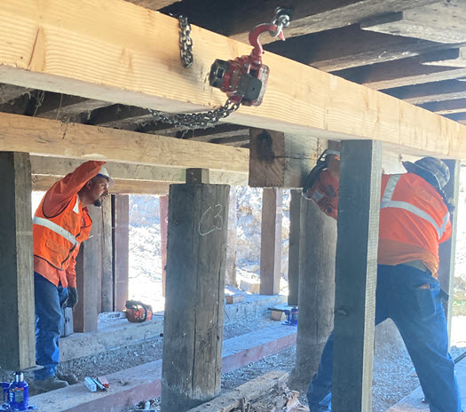 Two men working under a bridge
