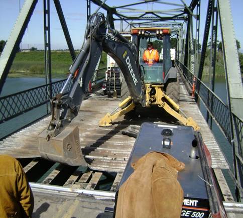 Maintenance workers using an excavator to remove debris from underneath Twin Cities Road Bridge.